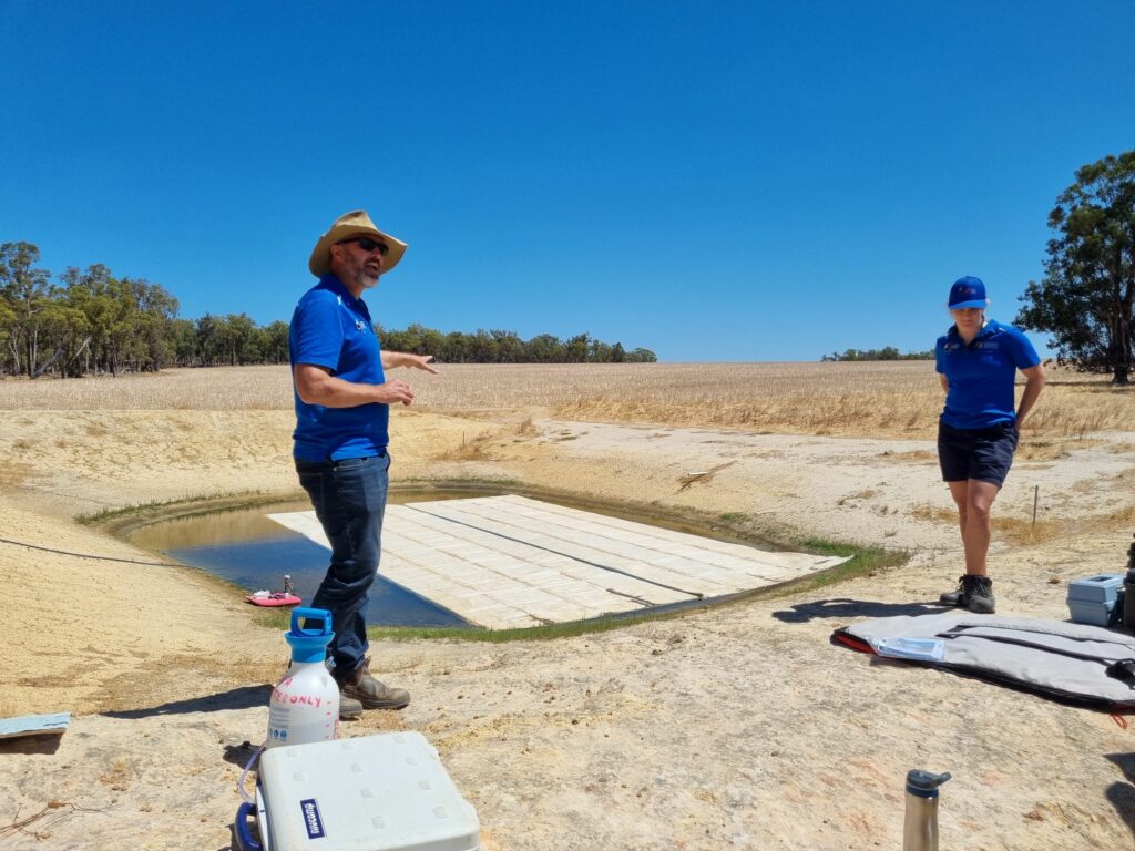 Two researchers standing on the edge of a farm dam